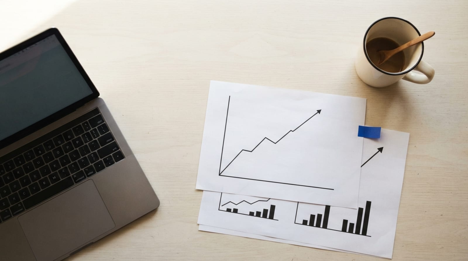 Printed search performance charts and a laptop on a lean marketing team's worktable