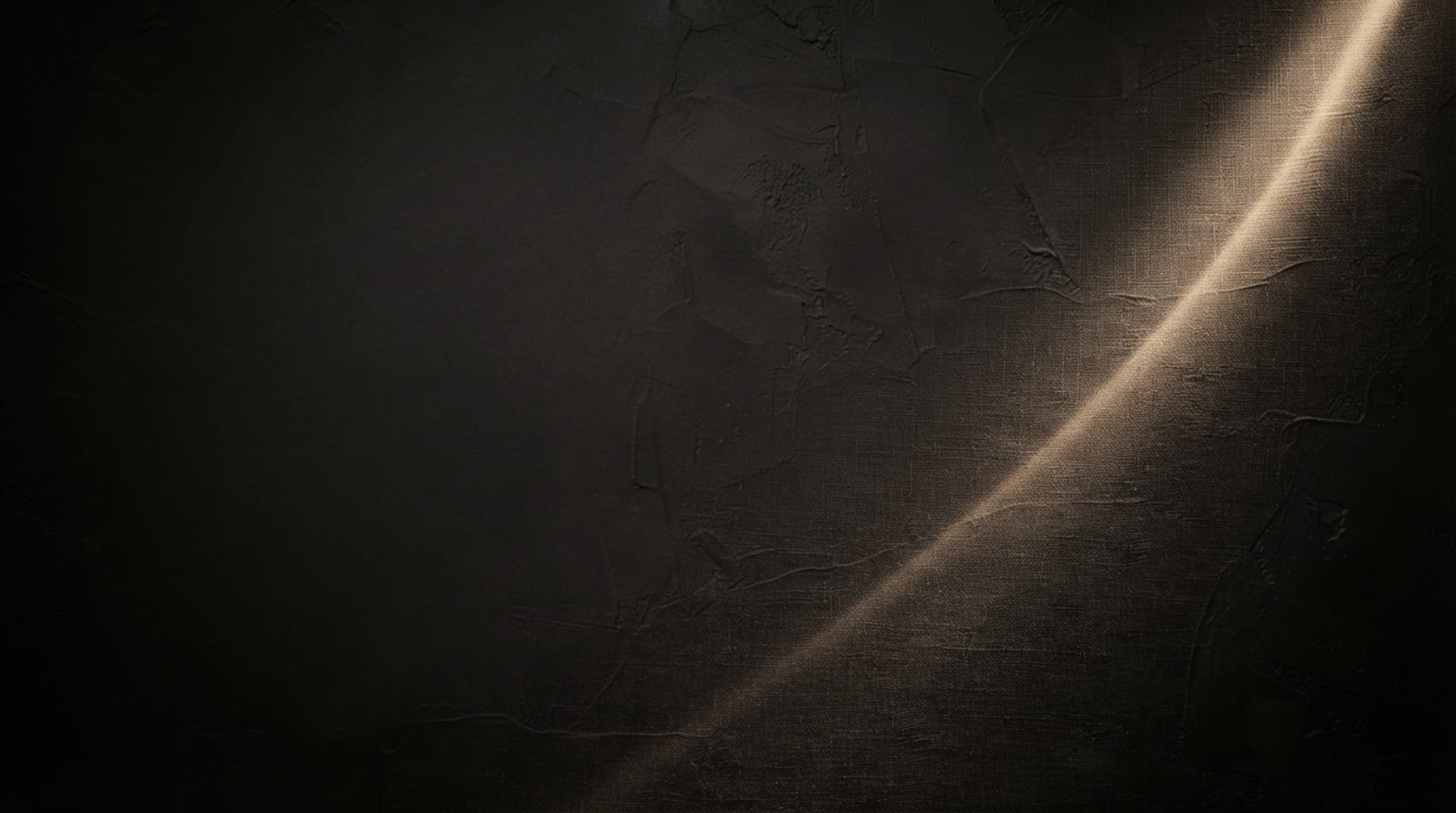Warm black plaster texture crossed by a thin beam of champagne light