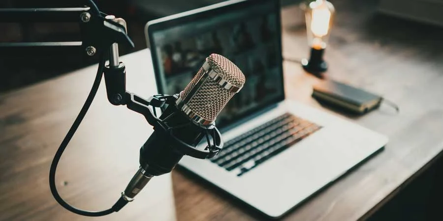 Podcast recording setup with a studio microphone and a laptop on a desk