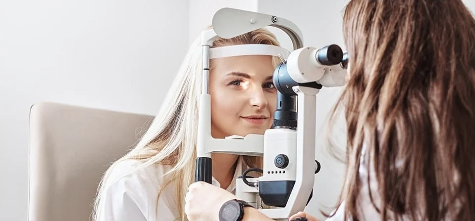 Patient having an eye exam at a slit lamp with a clinician
